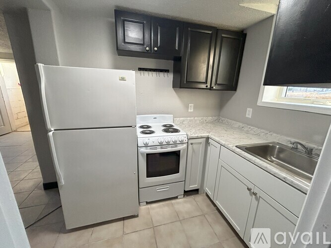 A kitchen with a white refrigerator, stove, and sink.