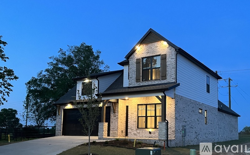 A house with a garage and a driveway is illuminated by lights.