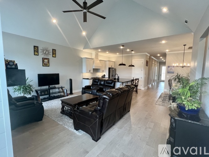 A spacious living room with a black leather sofa and a television.