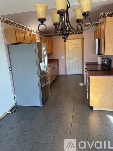 A kitchen with a refrigerator, microwave, and wooden cabinets.