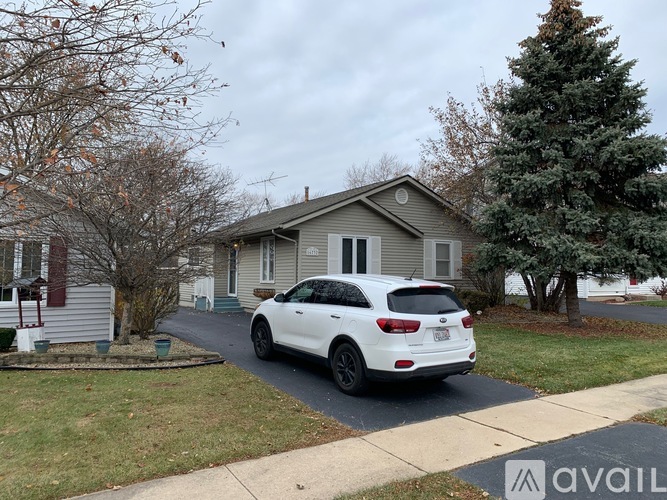 A white car is parked in front of a house.