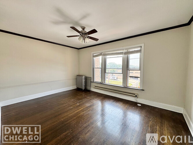 A room with a ceiling fan and a window with a view of a building outside.