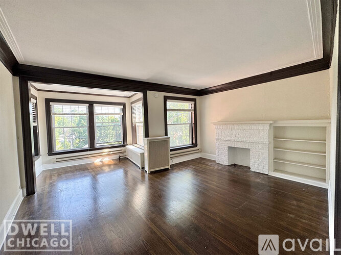 A spacious room with wood flooring and a fireplace.