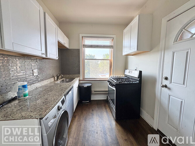 A kitchen with a black stove top oven and a washer and dryer in it.