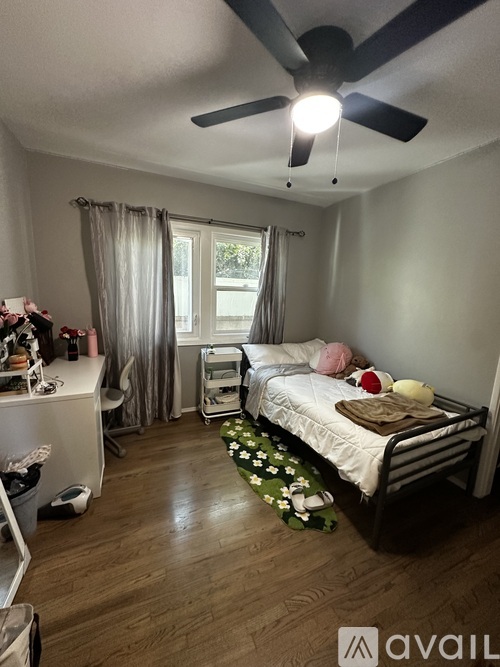A bedroom with a bed, a dresser, and a ceiling fan.