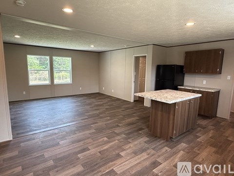 A spacious room with wood flooring and a kitchenette.