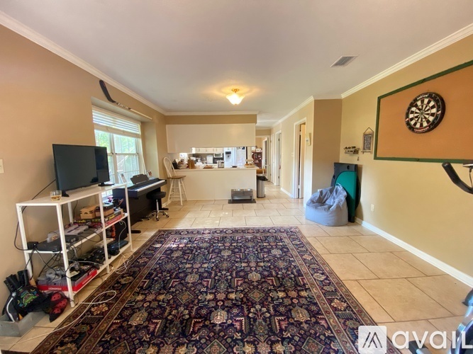 A living room with a rug on the floor and a television on the left side.