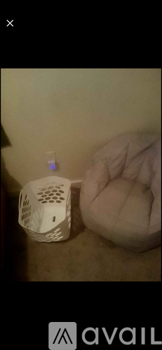 A white speaker is placed on a carpet next to a white bean bag chair.