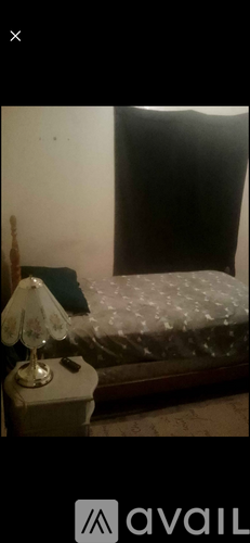 A lamp sits on a bedside table next to a bed.
