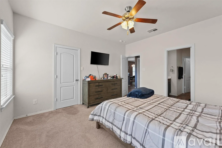 A bedroom with a bed, dresser, and ceiling fan.