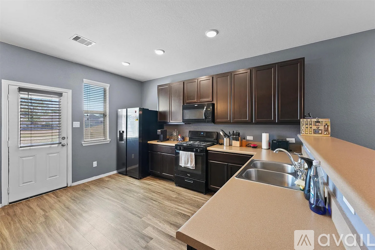 A kitchen with brown cabinets and a black fridge.