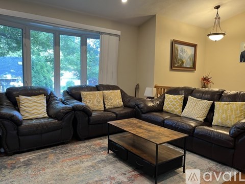 A living room with a black leather couch and a coffee table.