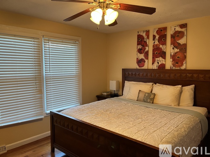 A bedroom with a bed, ceiling fan, and window with blinds.