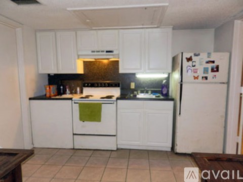 A kitchen with white cabinets and a refrigerator with magnets on it.