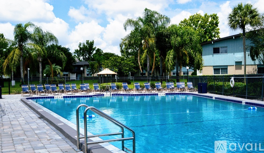 A swimming pool surrounded by palm trees and lounge chairs.
