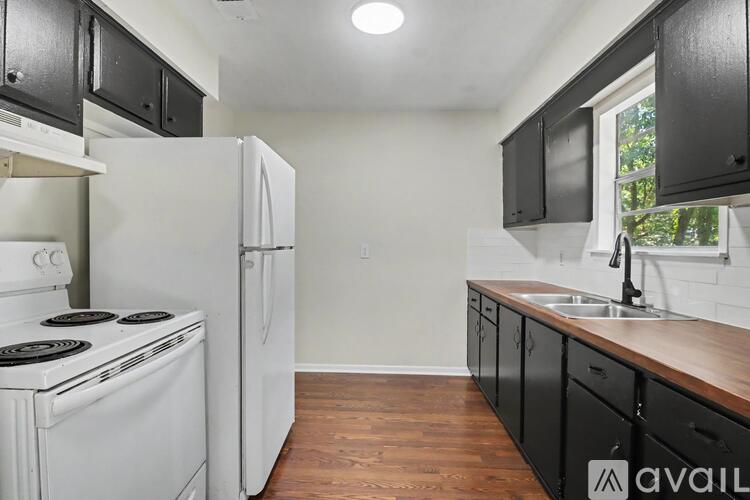A kitchen with black cabinets and white appliances.