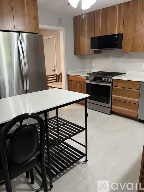 A kitchen with a table and chairs in the foreground and a refrigerator and microwave above the stove in the background.