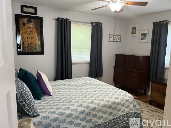 A bedroom with a patterned bedspread and a ceiling fan.