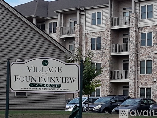 A sign that says "Village of Fountainview" stands in front of a building.