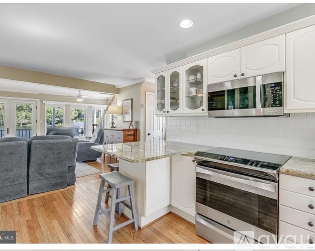 A kitchen with white cabinets and a marble countertop.