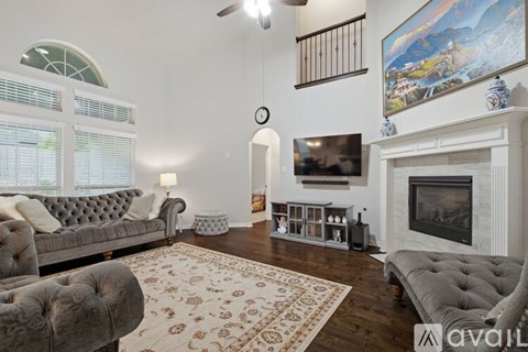 A living room with a grey couch, a fireplace, and a painting on the wall.