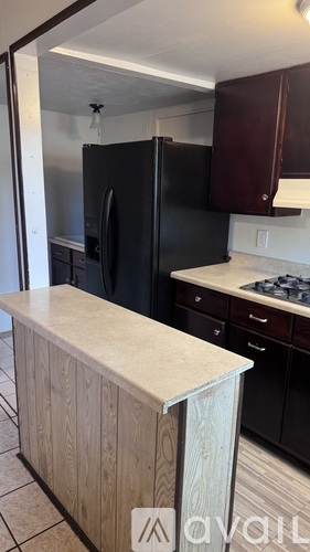 A kitchen with a black refrigerator and wooden island.