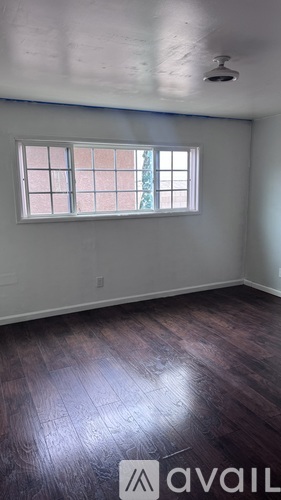 A room with a window and wooden flooring.
