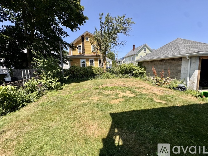A backyard with a large grassy area and a house in the background.