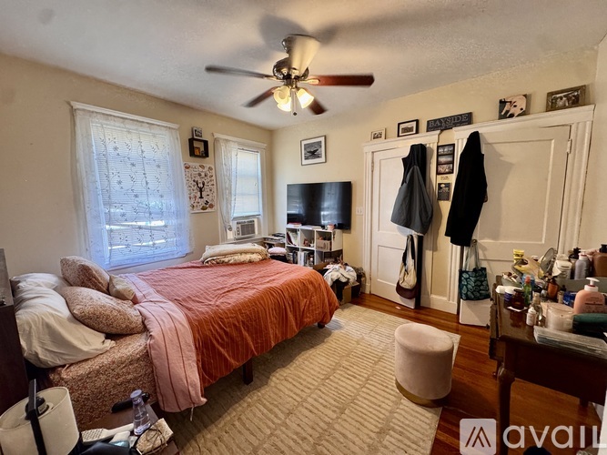 A bedroom with a bed, a chair, a dresser, and a ceiling fan.