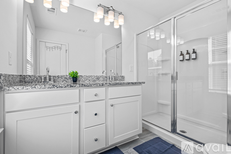 A bathroom with a marble countertop and white cabinets.