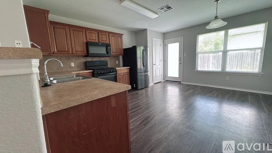 A kitchen with wooden cabinets and a black refrigerator.