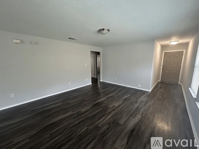 A room with wooden flooring and a door in the middle.