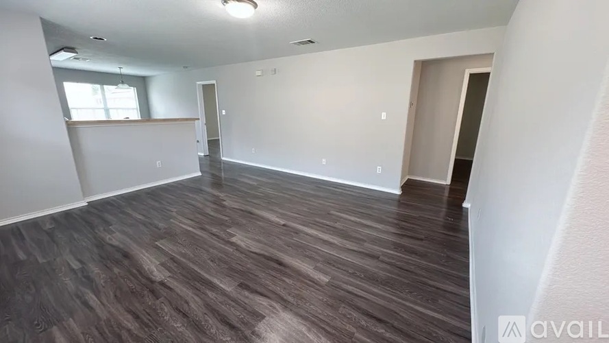 A spacious room with wooden flooring and white walls.