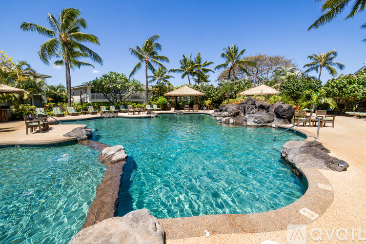 A large swimming pool surrounded by palm trees and lounge chairs.