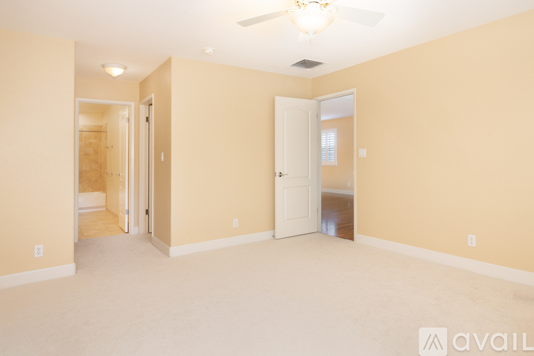 A spacious room with a ceiling fan and two doors.