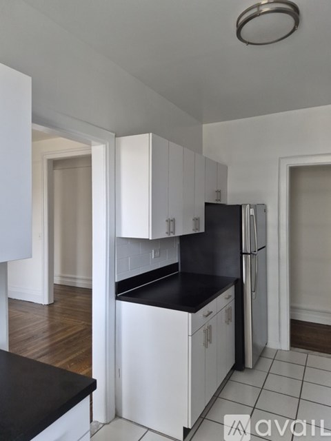 A kitchen with white cabinets and a black countertop.