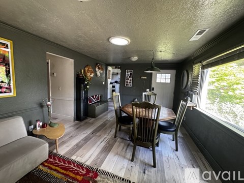 A living room with a grey couch, a wooden table and chairs, and a rug on the floor.