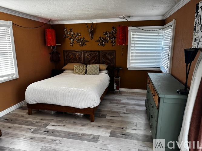 A bedroom with a bed, dresser, and wall decorations.
