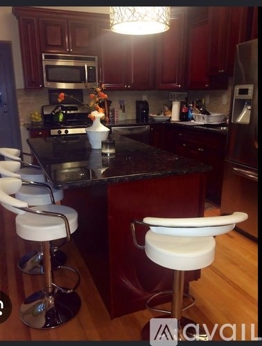 A kitchen with a black counter top and white stools.