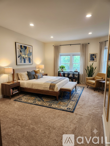 A bedroom with a large bed and a rug on the floor.
