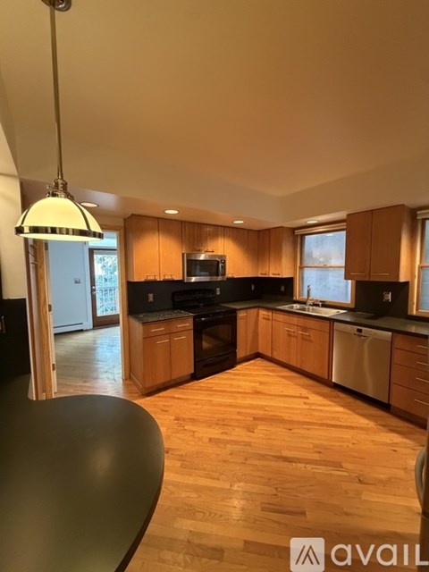 A kitchen with wooden cabinets and black countertops.