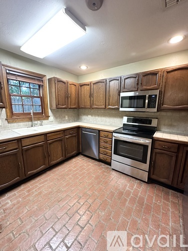A kitchen with wooden cabinets and a brick floor.