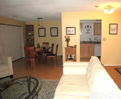 A living room with a white couch and a dining table with chairs.