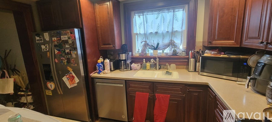 A kitchen with a refrigerator covered in magnets and a window with curtains.