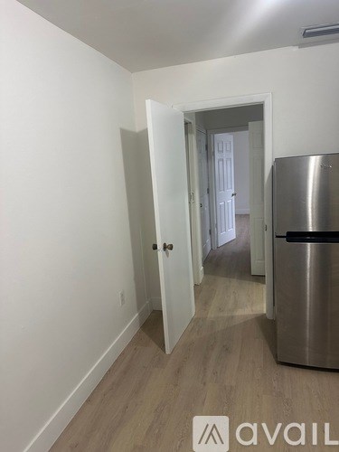 A kitchen with a stainless steel refrigerator and wooden flooring.