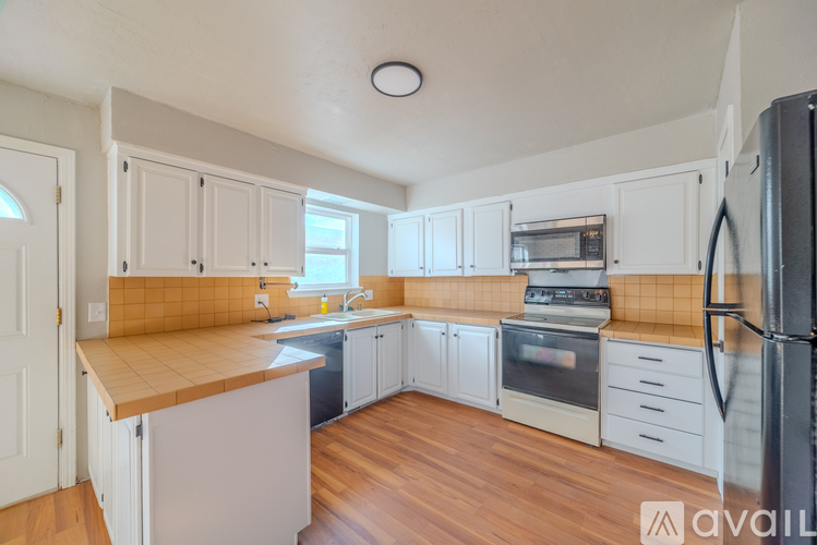 A kitchen with white cabinets and a black fridge.