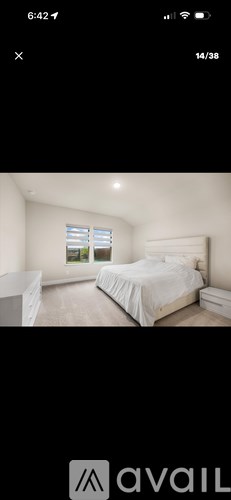 A bedroom with a large bed and a window with blinds.