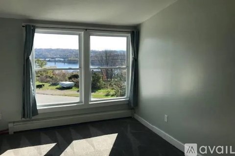 A room with a large window overlooking a lake and a car parked outside.
