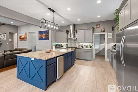 A modern kitchen with blue cabinets and stainless steel appliances.
