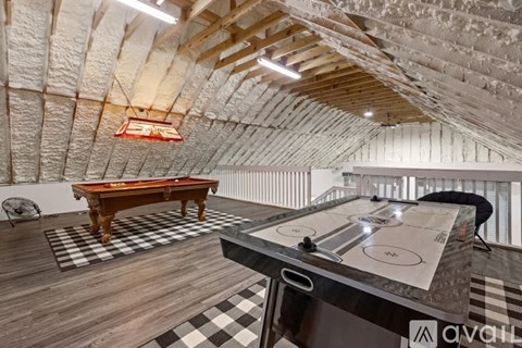A pool table in a room with a brick wall and wooden ceiling.